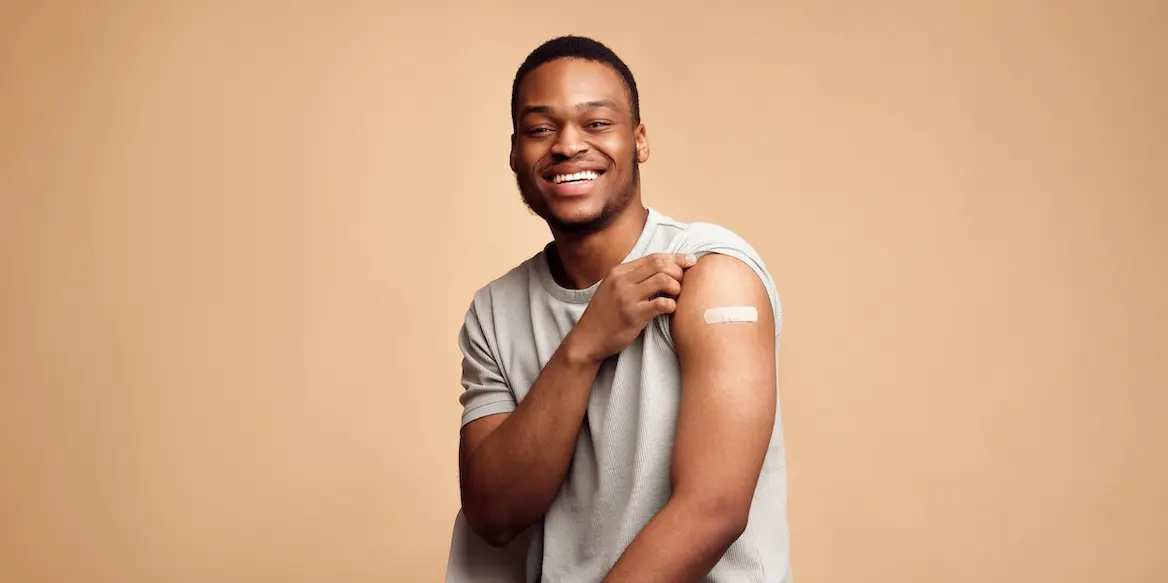 Covid-19,Vaccinated,African,Man,Showing,Arm,With,Plaster,,Beige,Background